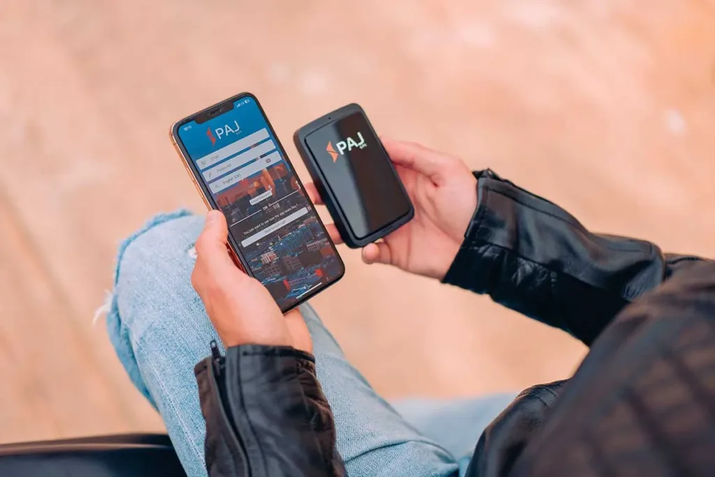 A man holding ALLROUND Finder 4G and a mobile phone in which Finder Portal is opened in it