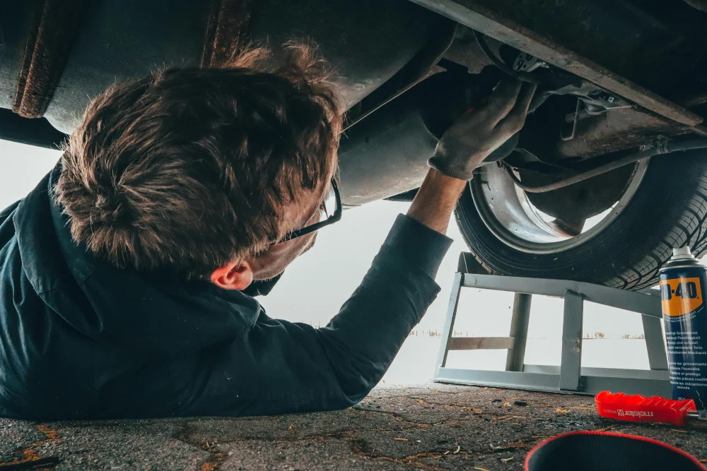 man under the car checking the exhaust system