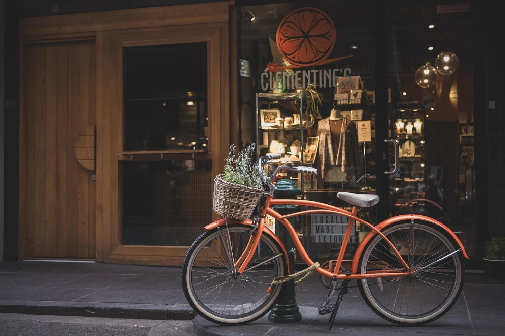a bike parked near a shop with the front wheel have lock wrapped around the nearby piller